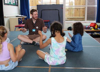 staff member leading circle games with three children