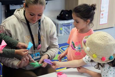 Staff member showing children how to make oragami animals