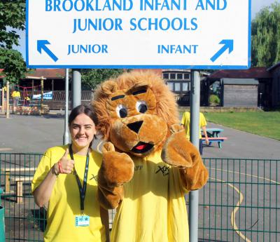 staff member and lion mascot posing with thumbs up