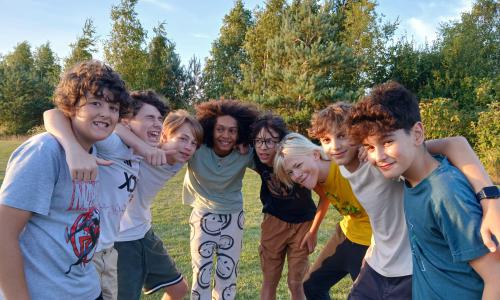 Group of children smiling arm in arm while at summer camp