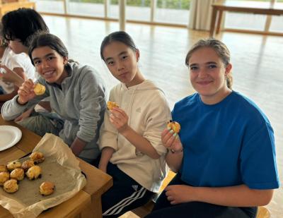 Three teenage girls smiling while eating scones at summer camp in the UK