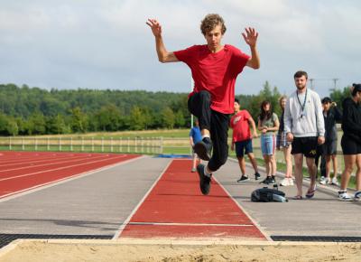 teenage boy doing long jump athletics at a sports summer camp near me